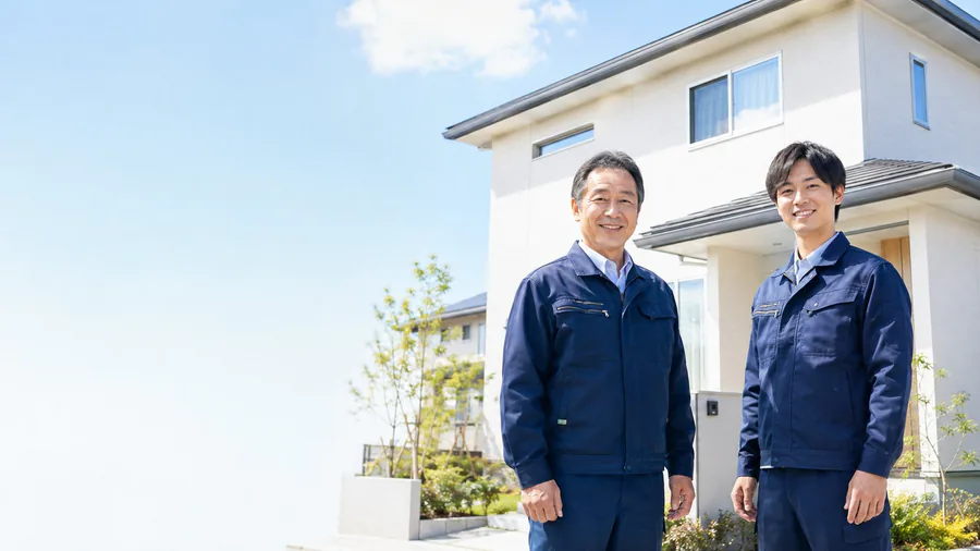 住宅の前に立つ作業服のスタッフ2人(イメージ)